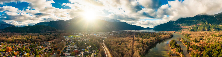 Aerial panoramic view of a small town with Chief Mountain in the background during a sunny sunrise. Taken in Squamish, North of Vancouver, British Columbia, Canada.