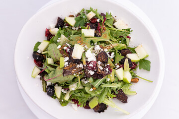 Overhead view of large bowl of salad topped with prunes and croutons.