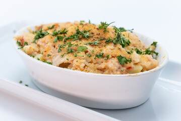 Lobster macaroni and cheese served hot in a casserole plate topped with fresh basil