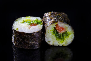 Japanese Cuisine. Macro Shoot of Two Traditional Sushi Rolls With Salmon and Laminaria Together on Black