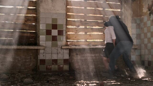 criminal holds hostage by threatening with pistol near window in abandoned building. offender is covered for victim.