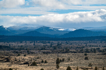 Clouds rolling over the snowy mountains behind Devil's Homestead at Lava Beds National Monument near Tulelake, California, USA