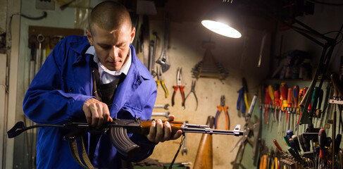 Gunsmith with Kalashnikov assault rifle in a weapons workshop