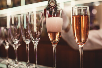 Line of alcohol setting on catering banquet table, bartender pouring beverages, row of different colored alcohol cocktails on a party, martini, vodka, and others on decorated banquet table event