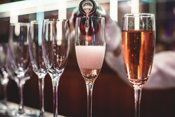 Line of alcohol setting on catering banquet table, bartender pouring beverages, row of different colored alcohol cocktails on a party, martini, vodka, and others on decorated banquet table event