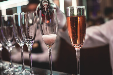 Line of alcohol setting on catering banquet table, bartender pouring beverages, row of different colored alcohol cocktails on a party, martini, vodka, and others on decorated banquet table event