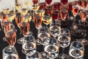 Line of alcohol setting on catering banquet table, bartender pouring beverages, row of different colored alcohol cocktails on a party, martini, vodka, and others on decorated banquet table event