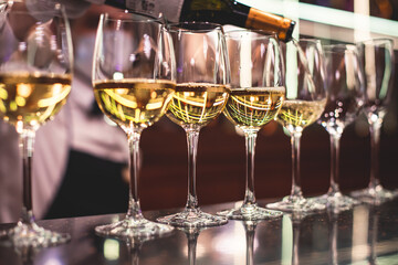 Line of alcohol setting on catering banquet table, bartender pouring beverages, row of different colored alcohol cocktails on a party, martini, vodka, and others on decorated banquet table event