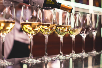 Line of alcohol setting on catering banquet table, bartender pouring beverages, row of different colored alcohol cocktails on a party, martini, vodka, and others on decorated banquet table event