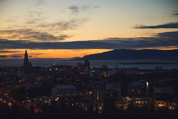 Beautiful night dusk view of Reykjavik, Iceland, aerial view with Hallgrimskirkja lutheran church, with scenery beyond the city, Esja mountain and Faxafloi bay