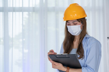 Female Engineer wear face mask with safety yellow helmet standing inside building check the correctness of the construction.