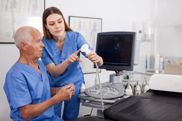 Fototapeta premium Portrait of young efficient friendly technician showing new ultrasound scan to doctor in clinic