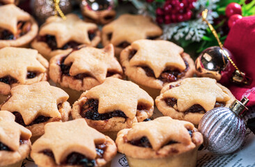 Many small round Christmas cupcakes with a star on top and seasonal decorations