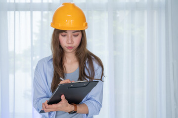 Female Engineer with safety yellow helmet standing inside building check the correctness of the...