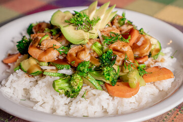 Delicious shrimp teriyaki with broccoli, pumpkin, carrot and rice in oyster sauce on a white plate.
