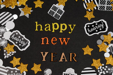 Happy new year, phrase made with colorful letters and golden stars and confetti on black background