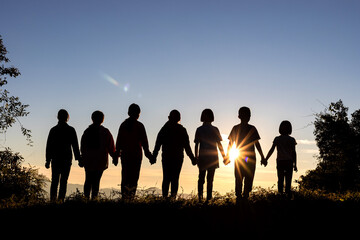 Silhouette of group children standing on mountain at sunset