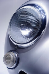 Retro car headlight with chrome parts on hood, vintage vehicle with silver bodywork, classic sedan, automobile industry 