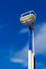 Hydraulic lift platform with bucket, construction industry, blue sky and white clouds on background 
