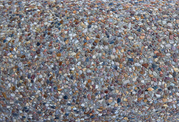 texture of stones in a light-colored concrete fence, crushed stone