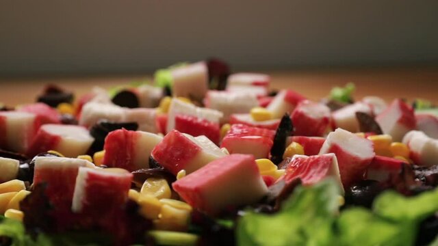 Gastronomy. Healthy food and nutrition. Panning a fresh gourmet salad dish with corn grains, lettuce, cucumber, black olives and crab sticks.