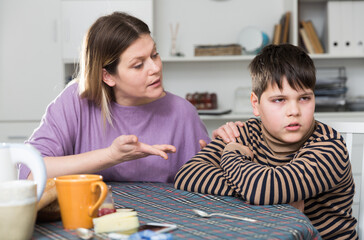 Upset boy and angry mother having quarrel during breakfast at home. High quality photo