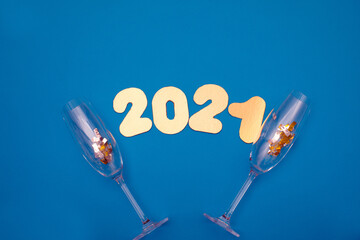 Gold numbers 2021 on blue background. New year celebration. Happy New Year 2021 with glasses of champagne and confetti