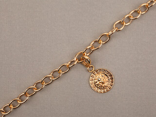 Golden pendant with chain on beige textured background