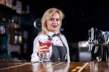 Girl barman mixes a cocktail on the public house