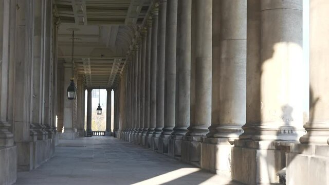 A panning shot of a corridor with rows of columns.
