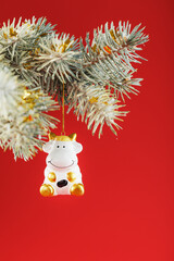 A figurine of a cow on a Christmas card on a red background, free space for text.