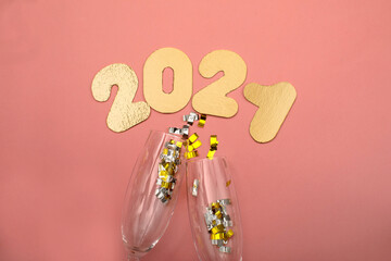 Gold numbers 2021 on pink background. New year celebration. Happy New Year 2021 with glasses of champagne and confetti
