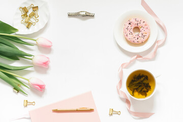 Spring flat lay with a bouquet of pink tulips. A woman's workplace. Tea break with Donat. Copy space