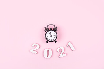 Wodden 2021 Creativity ideas concepts with little clock on pink color background. New years content.