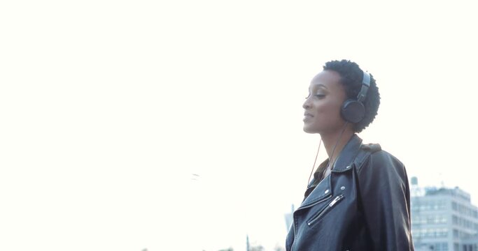 Close up of female feet in high heels step on sidewalk, human body rhythmically moves to music. Young African teenager wears stylish clothes, wears earphones on her head and dances, selective frame