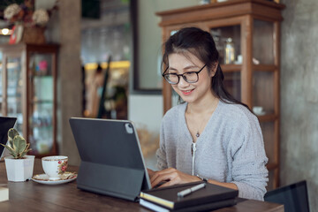 Attractive asian woman working with a digital tablet in a coffee shop.
