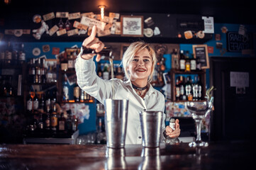 Fototapeta na wymiar Girl bartender concocts a cocktail at the public house