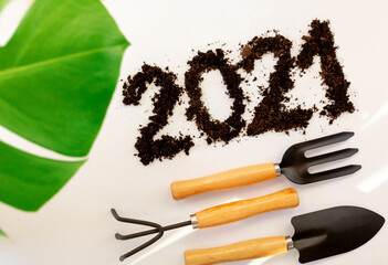 2021 made of brown fertile soil isolated on white with shovel. rake,monstera leave, agriculture and...