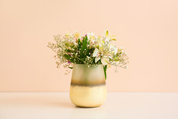 Beautiful vase with bouquet of flowers on light table against color background