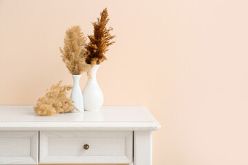 Beautiful vases with pampas grass on light table against color background