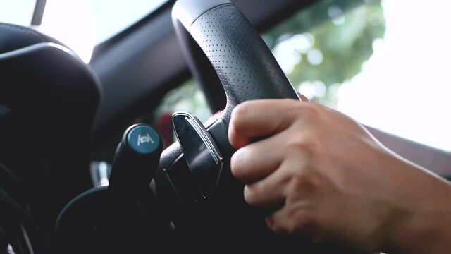 Close-up of a woman holding a steering wheel and pushing a gear shift knob using the Paddle Shift and getting better driving power. Transportation Concept.