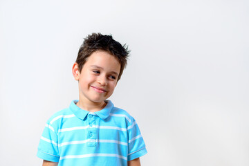 A boy in a blue T-shirt smiles slyly and looks at the camera.