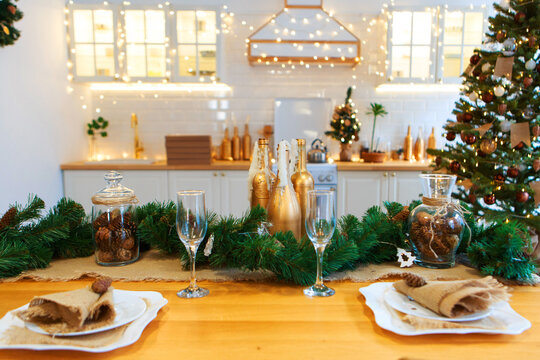 Gala Dinner. Cooking At Christmas. New Year's Interior In The Kitchen. Decorations: Christmas Tree, Garland, Cones And Glasses, Gold And Green