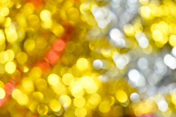 Gold bokeh background. Texture with shining blurred lights in yellow, red and silver. Abstract Christmas festive background. Blurry lights of gold color.