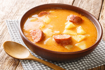 Homemade potato soup with sausages and sour cream close-up in a plate on the table. horizontal