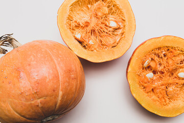 Minimalistic still life with pumpkins, whole and halves on a light background. Autumn concept with space for text