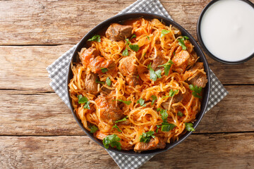 Szeged sauerkraut goulash with pork and paprika close-up in a plate on the table. horizontal top view from above