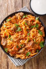 Hungarian Szegedin Goulash features slow simmered, succulent pork, onions and sauerkraut in a wonderfully rich paprika infused broth in the plate on the table. Vertical top view from above