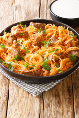 Szekely Gulyas or Szegedin goulash with pork, onions and sauerkraut in a paprika broth closeup  in the plate. Vertical