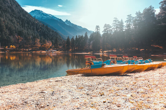 A group of catamarans is moored on the shore of the Kara-Kel lake beach in Teberda. Autumn sunny day. Mountains and forest in the background